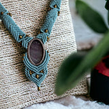 Ayana Crystals amethyst macrame necklace featuring a blue cord design with brass beads on a textured display stand