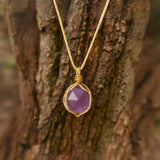 Ayana Crystals raw amethyst necklace in a macrame cord setting against a rustic tree bark background