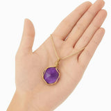 Ayana Crystals raw purple amethyst pendant necklace in a tan macrame cord held in a palm for scale